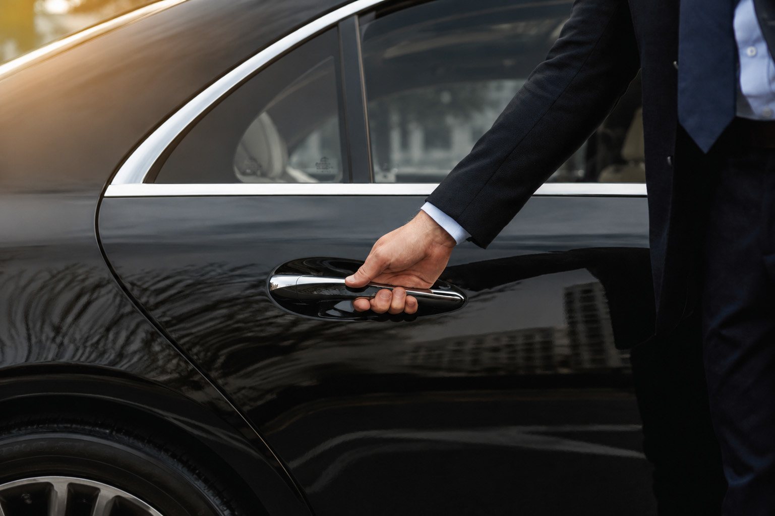 A VOGA chauffeur opens the rear door onto cream leather.